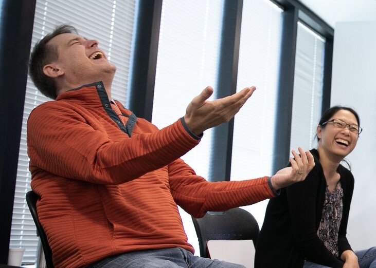Workshop particpants laughing with hands raised