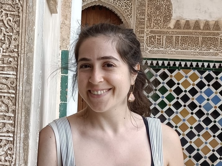 Sandy Abu El Adas     Person smiling, standing in front of ornate tile work and carved wooden door