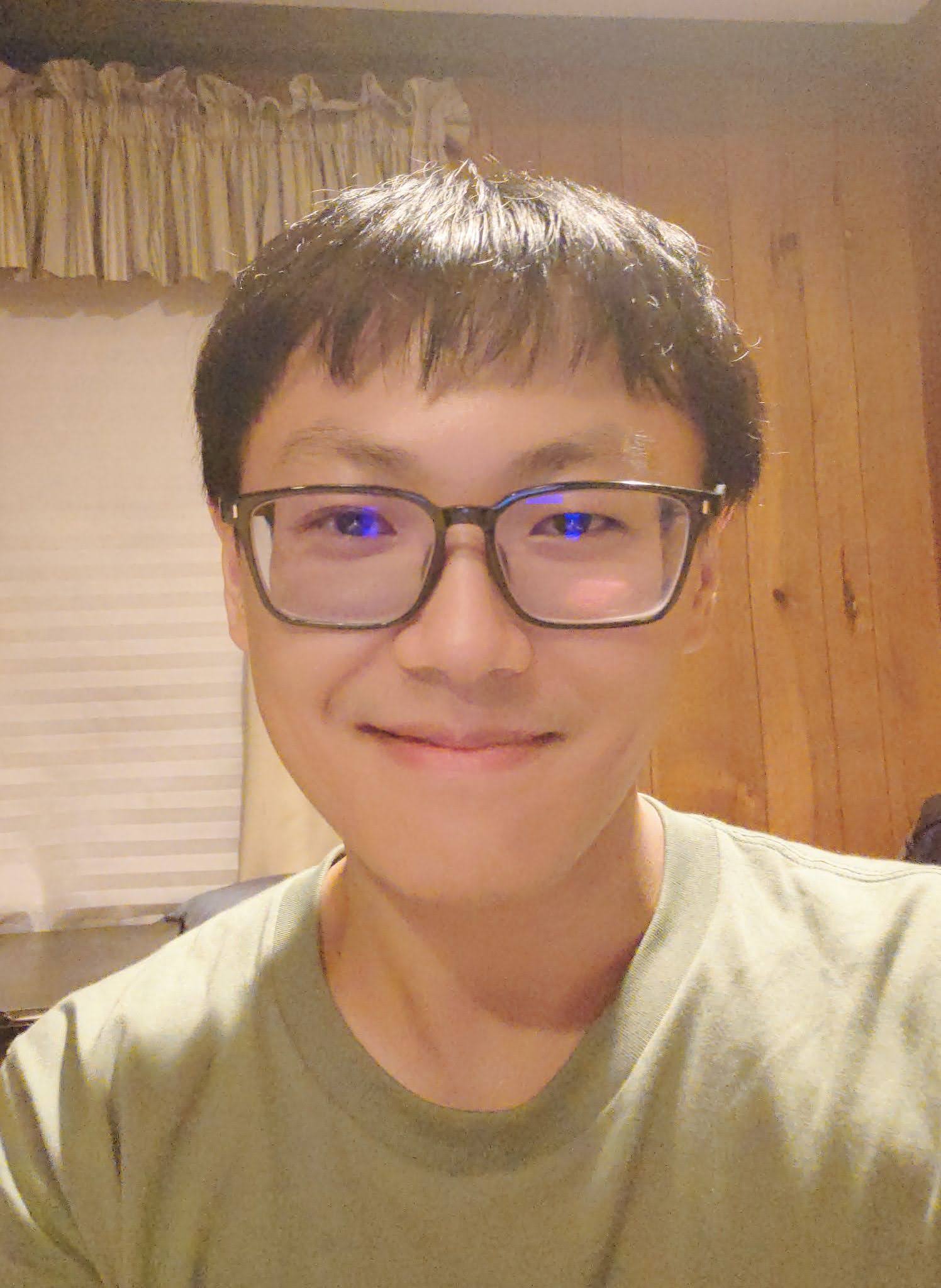 Kuan-Wen Chen Person with glasses smiling at the camera in a room with a curtained window in the background.