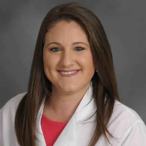 Jenna Palladino Portrait of a smiling healthcare professional in a white coat over a red top, set against a gray background.