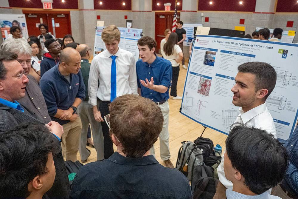 Group of students and professors around research project board